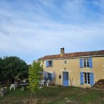 Maison aux volets bleus adossée à la colline, calme absolu au milieu des champs